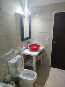 ein Badezimmer mit einer weißen Toilette und einem roten Waschbecken in der Unterkunft Los Delfines 2 in Mar de las Pampas + 10 Fotos