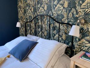 - un lit avec un oreiller bleu et un mur à motifs dans l'établissement A deux pas de la gare, La Maison Rouge, à Albertville