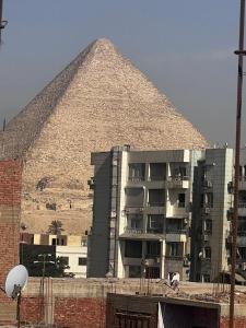 a large building with a pyramid in the background at Pyramid Heights Apartments in Cairo