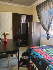 una camera con letto, tavolo e frigorifero di Siba's Place a Ga-Rankuwa