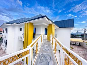 a white house with yellow columns and a balcony at Firnic Luxurious Private Hotel in Accra