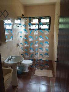 a bathroom with a toilet and a shower curtain with blue fish at Chalés Xibayka Ilhabela in Ilhabela