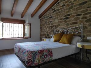 a bedroom with a bed and a stone wall at VillaManuela Vivienda Rural in San Vicente de Toranzo