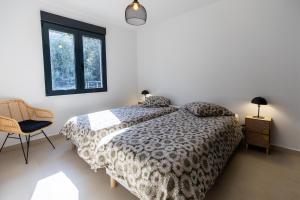 a bedroom with a bed and a chair and a window at Bonifacio Les Jardins ensoleillés de Piale in Bonifacio