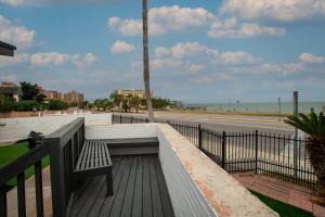 a bench on a boardwalk next to the beach at Luxury on Ocean Drive - Sleeps 28 in Corpus Christi