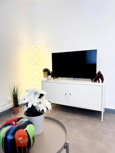 una sala de estar con TV de pantalla plana en un armario blanco en Le JOY, centre ville, en Mulhouse