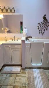 een badkamer met een wastafel, een bad en een spiegel bij Greentree Pacific House in Port Angeles