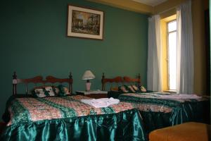 2 letti in una camera con pareti verdi di Hotel Las Lineas a Nazca