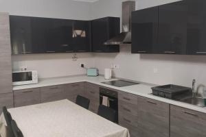 a kitchen with black cabinets and a table and a microwave at Cosy two bedroom maisonette in Xewkija