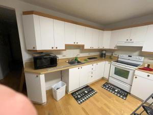 a kitchen with white cabinets and a sink and a microwave at Chambres à louer in Montréal