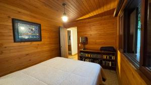 una camera da letto con letto bianco in una camera in legno di Casa Centro MONTE VERDE,MG 12 PESSOAS a Monte Verde