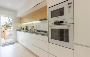 Una cocina con gabinetes blancos y un microondas. en Cozy Home In Torre De La Horadada, en Torre de la Horadada