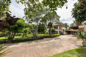a driveway with trees and houses in the background at Jaris Cottage in Nong Nam Daeng