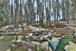 a green chair and a stone wall and trees at Spruce Creek Lodge: Classic A-Frame Mountain Retreat in Blue River