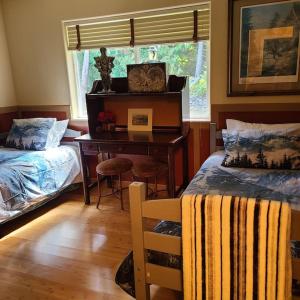 een slaapkamer met twee bedden, een bureau en een raam bij Greentree Pacific House in Port Angeles