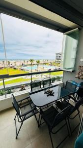 a table and chairs on a balcony with a view of the beach at Sidi Rahal Front mer, piscine & accès direct plage in Dar Oulad Hajj Kassem
