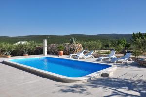 a swimming pool with lounge chairs next to it at House Sweet Dreams in Pučišća