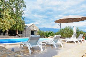 a group of chairs and an umbrella next to a pool at House Sweet Dreams in Pučišća