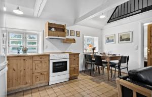 a kitchen with a table and a white stove top oven at 2 Bedroom Amazing Home In Blåvand in Blåvand