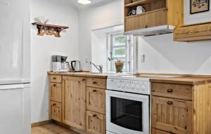 a kitchen with wooden cabinets and a white stove top oven at 2 Bedroom Amazing Home In Blåvand in Blåvand