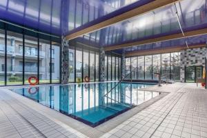 duży basen w budynku z oknami w obiekcie Apartament Glamour - 5 Mórz - Basen - SPA - Sauna w Sianożętach