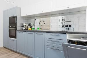 Biała kuchnia z białymi szafkami i urządzeniami w obiekcie Apartament Glamour - 5 Mórz - Basen - SPA - Sauna w Sianożętach