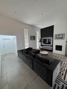 een woonkamer met een bank en een televisie bij Tinchley Havanna, Luxury 3 Bedroom home in Kaapstad