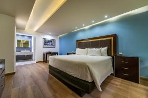 een slaapkamer met een groot bed met een blauwe muur bij Quinta Dorada Hotel & Suites in Saltillo