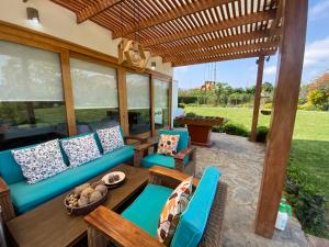 eine Terrasse mit einem blauen Sofa und Stühlen unter einer hölzernen Pergola in der Unterkunft Casa de campo en Hacienda San Andres in San Andrés