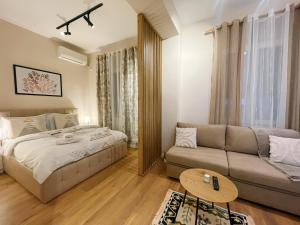 un soggiorno con un letto e un divano di AJ Apartments - Hidden Gem in front of Taiwan Center a Tirana
