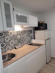 a kitchen with white cabinets and a sink at Le studio 29 in Le Barcarès