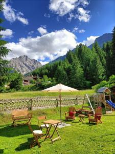 a group of picnic tables with an umbrella and a playground at B&B Agriturismo Cèsa Ciasates in Canazei