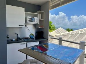 une cuisine avec une table et une vue sur l'océan dans l'établissement Appartements avec vue mer à Tartane, à La Trinité