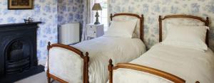 two beds in a bedroom with blue wallpaper at Brills Farm in Lincoln