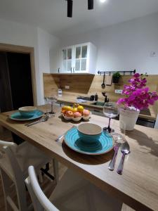 a wooden table with plates and wine glasses on it at Mozart apartman in Bijeljina +9 photos