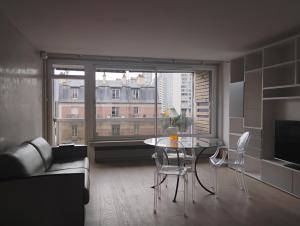 a living room with a table and chairs and a large window at Eiffel Tower spacious 2-bedroom, 2-bathroom quiet apartment, elegant and peaceful in Paris