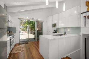 a kitchen with white cabinets and a large window at Coastal Delight In Kiama in Kiama