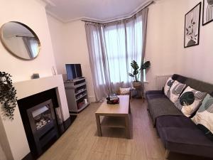 a living room with a couch and a fireplace at Spacious 3 bedroom house near Central London, O2, ExCel, Abba Voyage, Stratford, Tube Station & Parking Available in London