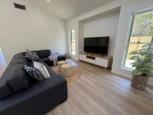 a living room with a black couch and a flat screen tv at 6 Yeri Drive - Rainbow Shores. Aircon. Pets Welcome. Walk to beach in Rainbow Beach