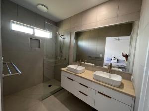 a bathroom with two sinks and a shower and a mirror at 6 Yeri Drive - Rainbow Shores. Aircon. Pets Welcome. Walk to beach in Rainbow Beach +14 photos