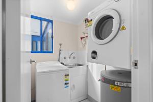 a white bathroom with a washing machine and a sink at Heritage 102 in Tuncurry