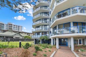 an apartment building with balconies and a sidewalk at Heritage 102 in Tuncurry