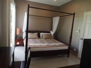 ein Schlafzimmer mit einem Himmelbett mit einem Holzrahmen in der Unterkunft Teddy Bear Villa Hua Hin in Cha-am