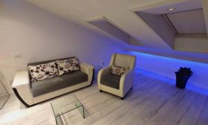 two chairs and a couch in a room with blue lights at Morning Wood - Skylight in Belgrade