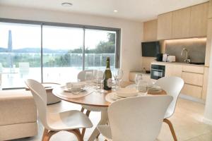 a dining room table with white chairs and a bottle of wine at RiverView GetAway in Maroochy River