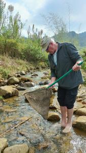 a man standing in a stream holding a net at Bình Bản Liền Homestay - Vang A Binh in Bắc Hà
