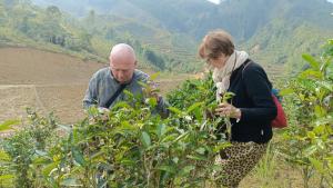 a man and a woman walking through a bush at Bình Bản Liền Homestay - Vang A Binh in Bắc Hà