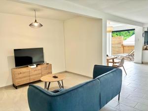 Una sala de estar con un sofá azul y un televisor. en East Lodge appartement, en Sainte-Luce
