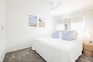 una camera bianca con letto bianco e cuscini blu di Sunrise Court a Bargara