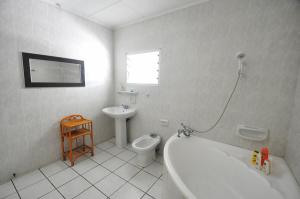 a bathroom with a tub and a toilet and a sink at Petit Baie Chalets in Au Cap